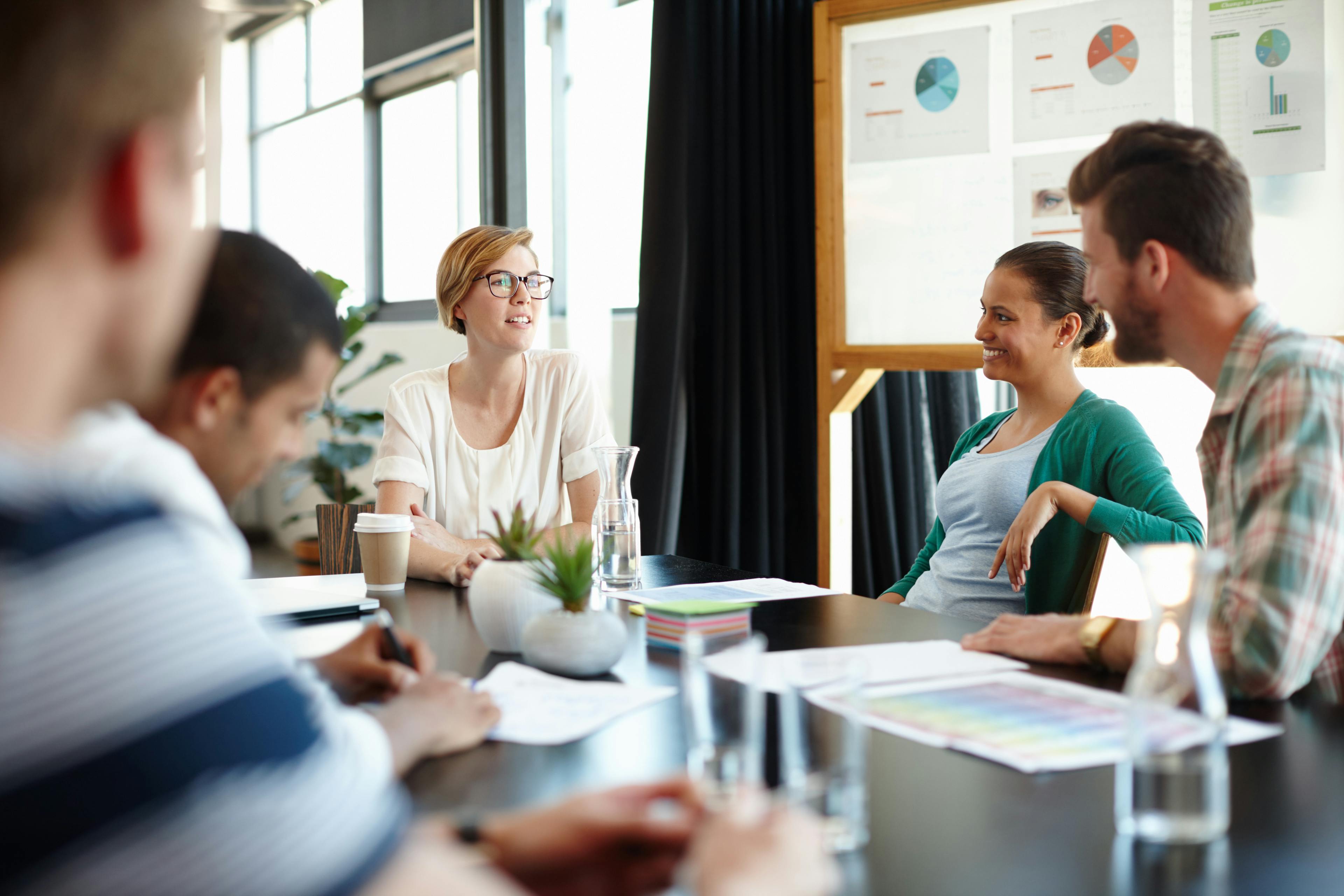 A group of employees sitting around a table together in a business meeting.