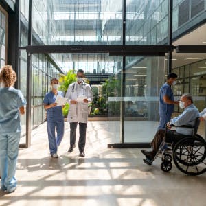 photo image of a healthcare facility corridor with nurses, doctors, and patients