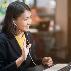 Photograph of person on video call with headphones in